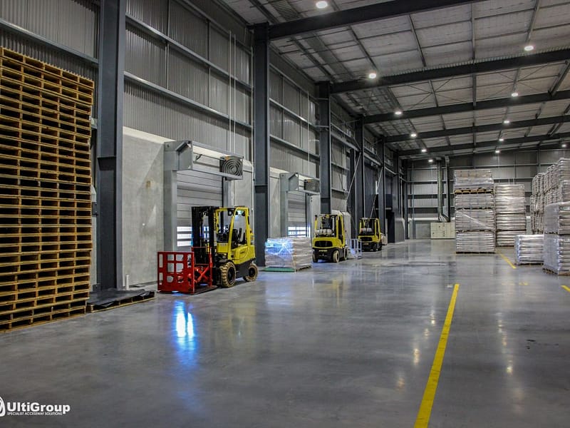 Yellow forklifts and stacked pallets in a warehouse with Ulti Spiral Doors.